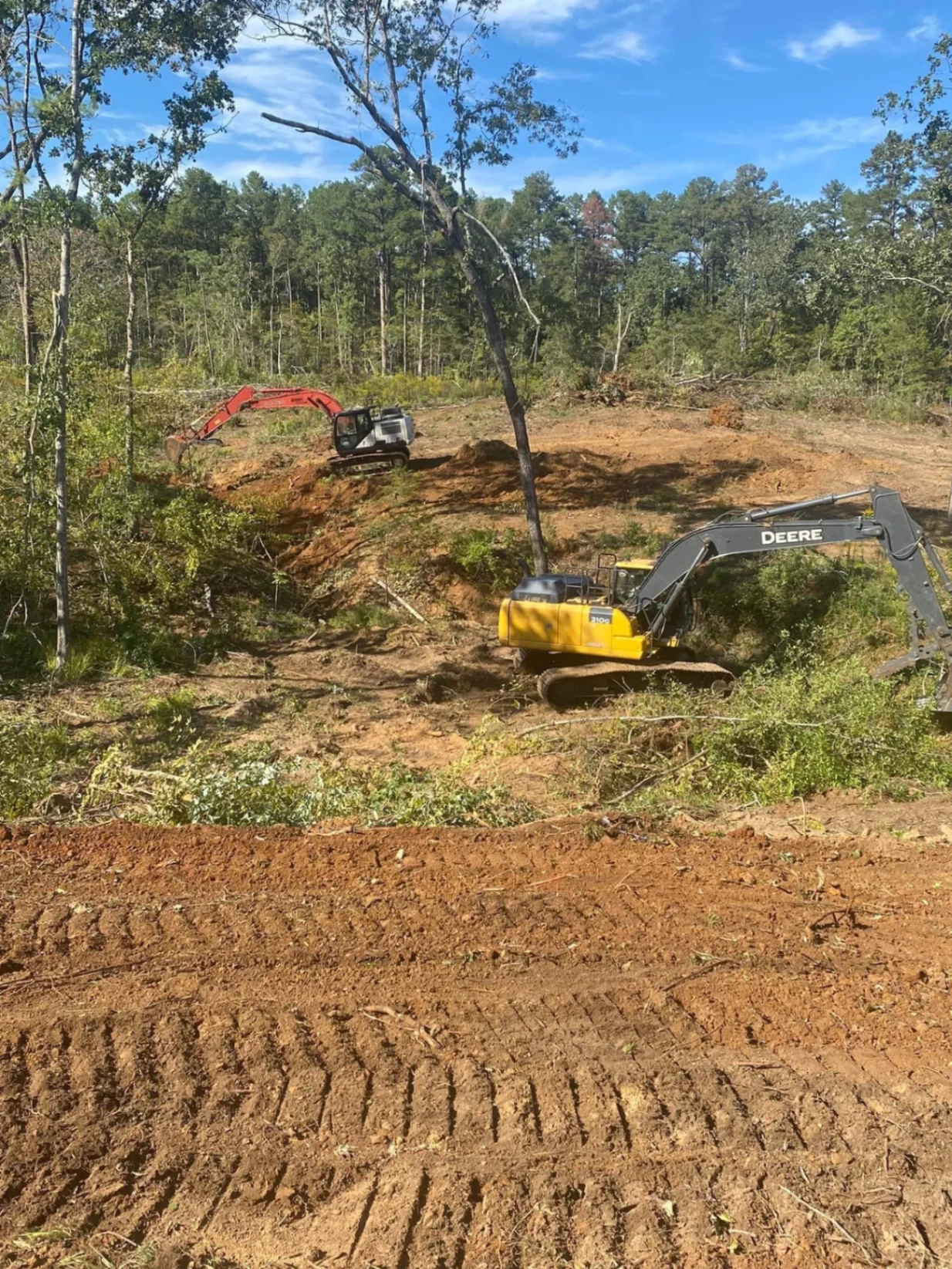 Excavators clearing brush and shaping a rural access road